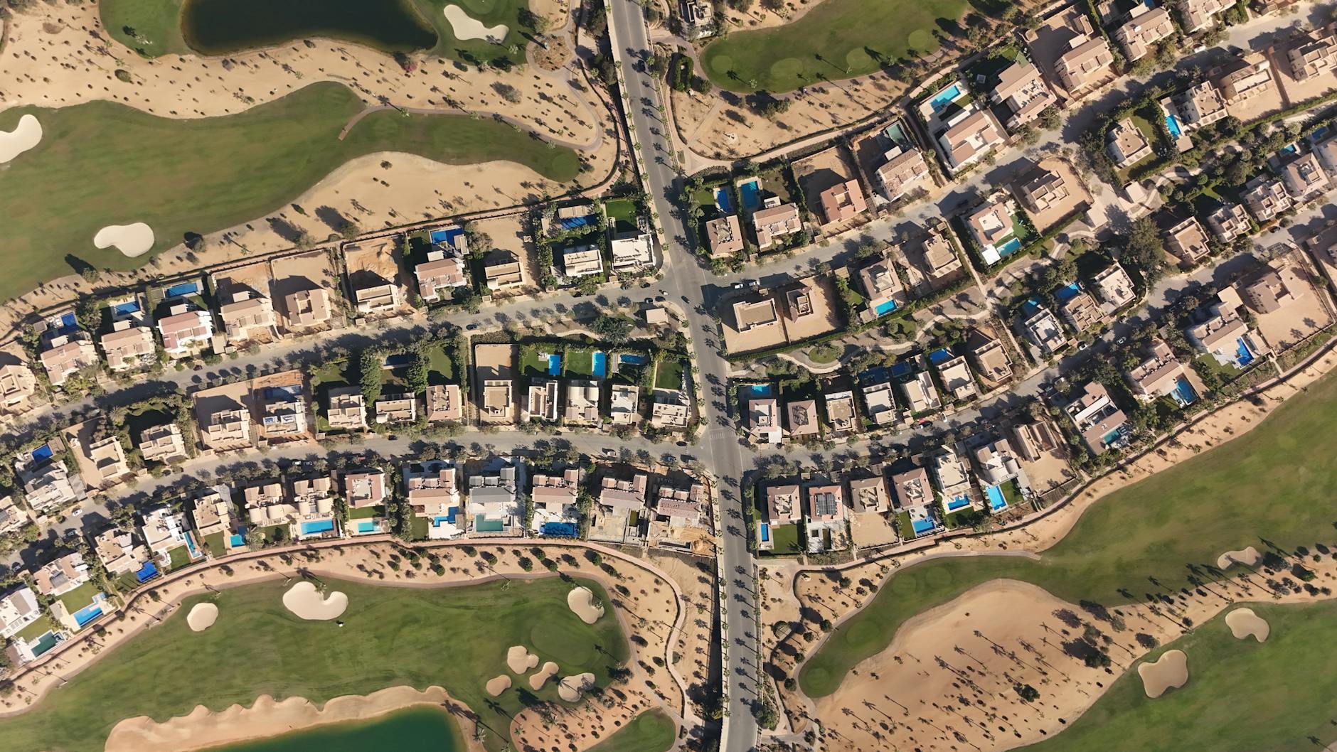 Vista aérea de vilas de luxo e campo de golfe em Sheikh Zayed, Cairo, mostrando arquitetura moderna e vegetação exuberante.