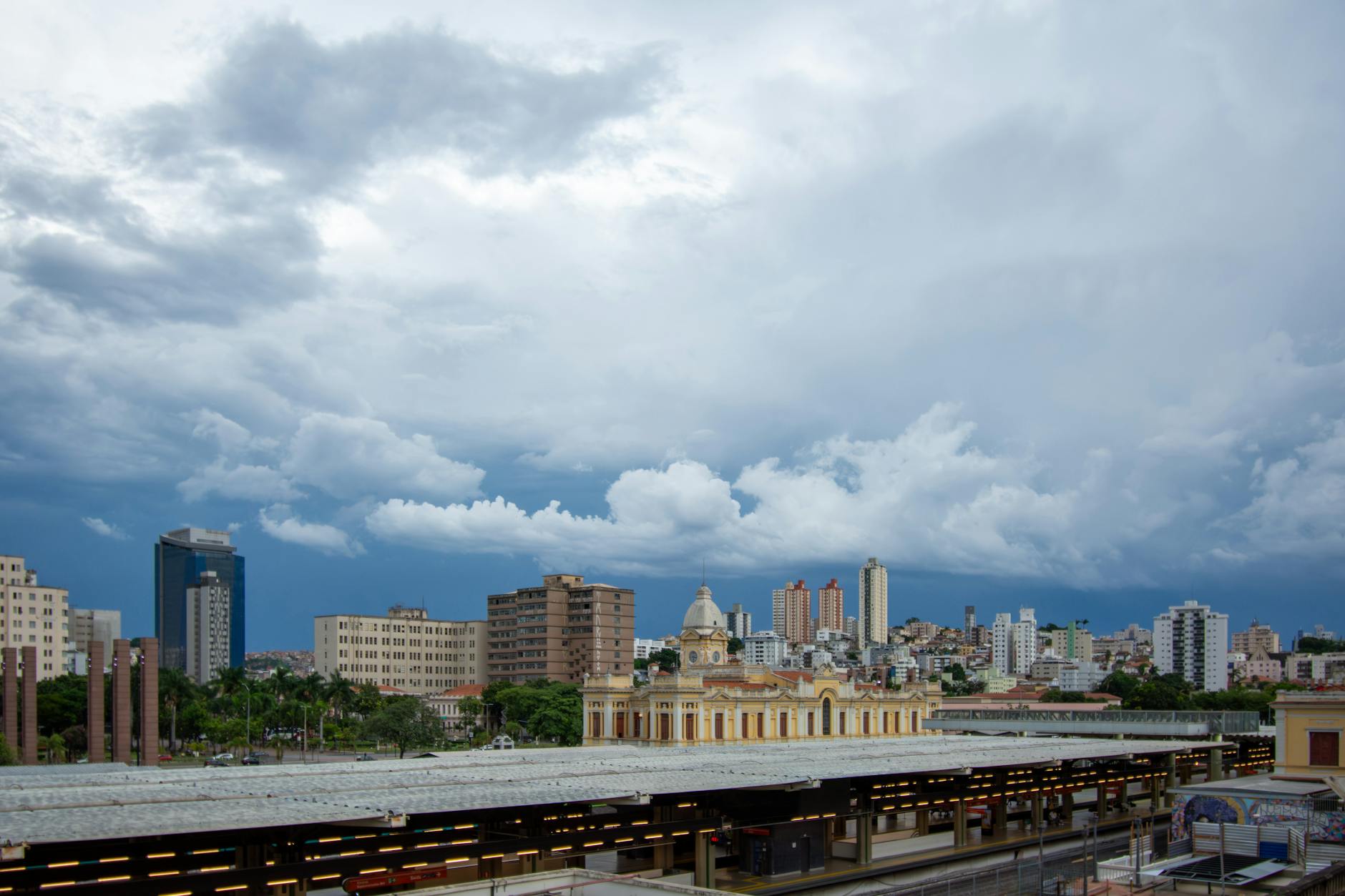 Vista panorâmica de Belo Horizonte com arquitetura histórica e céu nublado ao fundo.