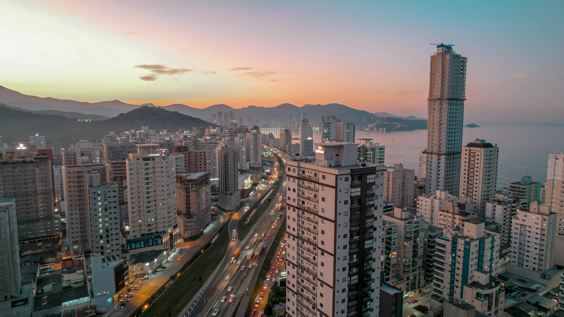 Vista aérea de Itapema, Santa Catarina, ao pôr do sol, mostrando a vibrante paisagem urbana e o litoral.