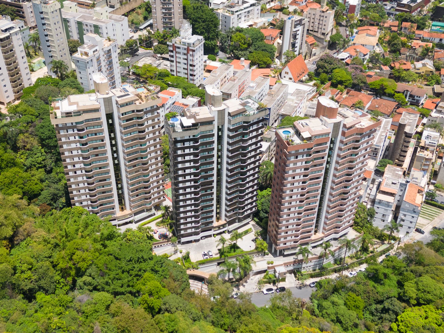 Vista aérea de modernos prédios de apartamentos cercados por exuberantes árvores verdes em Belo Horizonte, Brasil.
