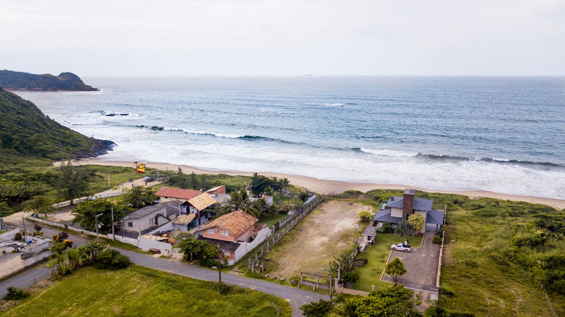 Vista aérea panorâmica de casas à beira-mar em Penha, Santa Catarina, Brasil, exibindo um belo litoral e vegetação exuberante.
