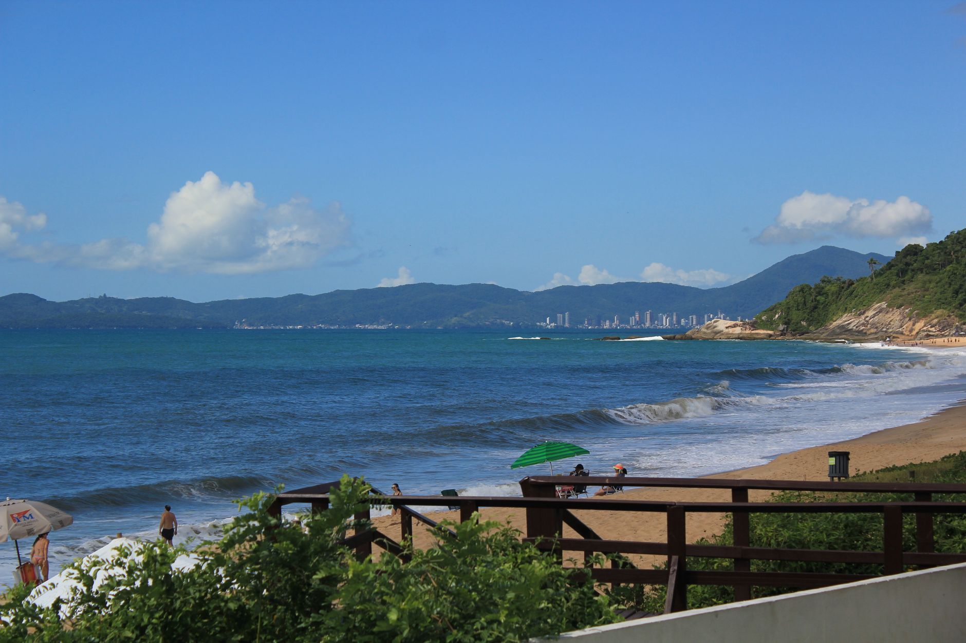 Linda cena de praia com ondas do mar e horizonte distante da cidade no Brasil.