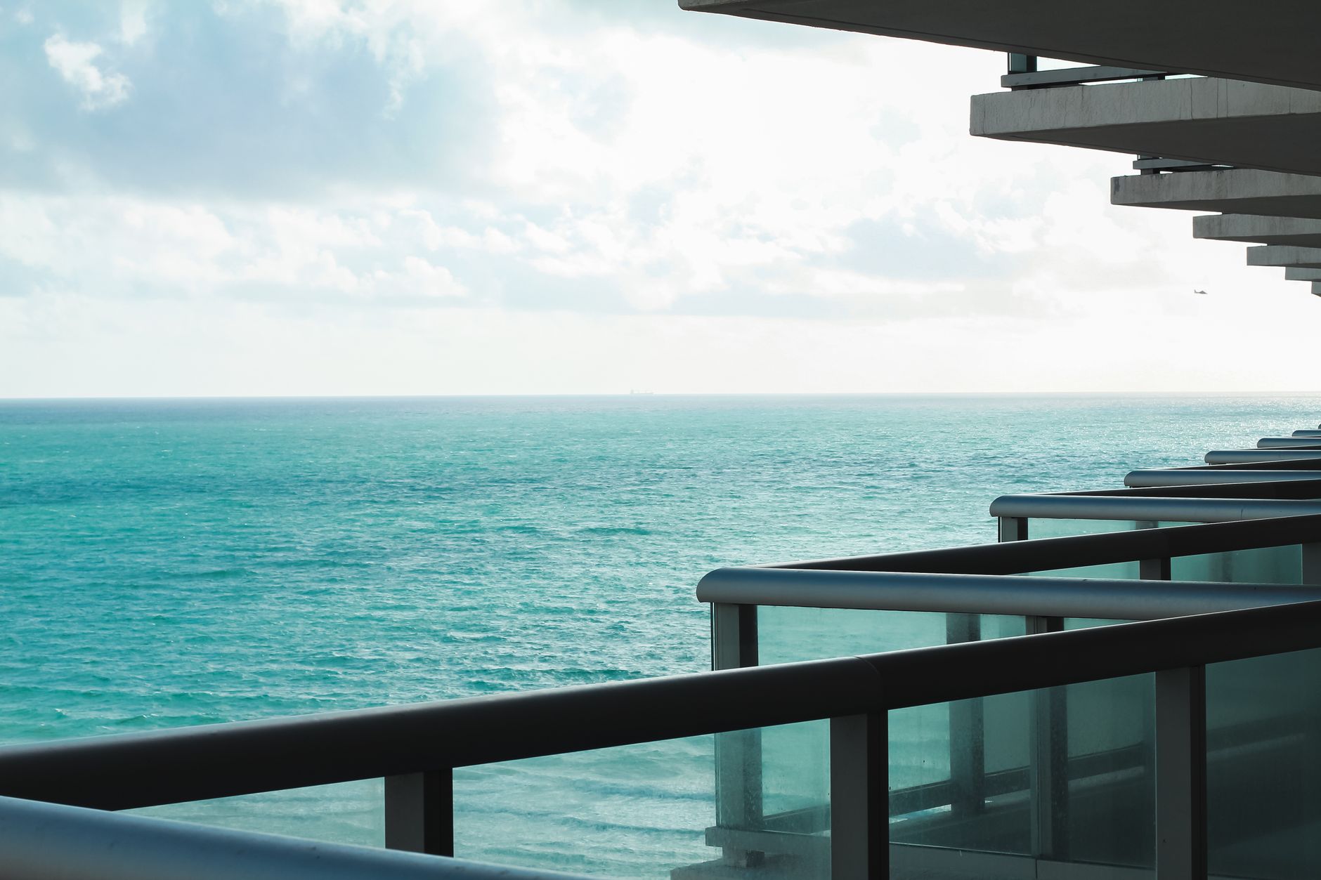 Varanda de apartamento moderno com vista para o mar em um dia ensolarado.