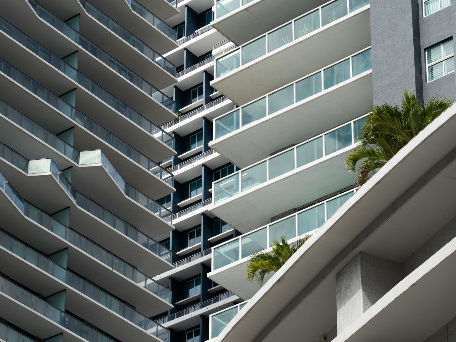 Vista aproximada da fachada de um moderno edifício residencial em Miami, destacando suas linhas elegantes e varandas espaçosas.