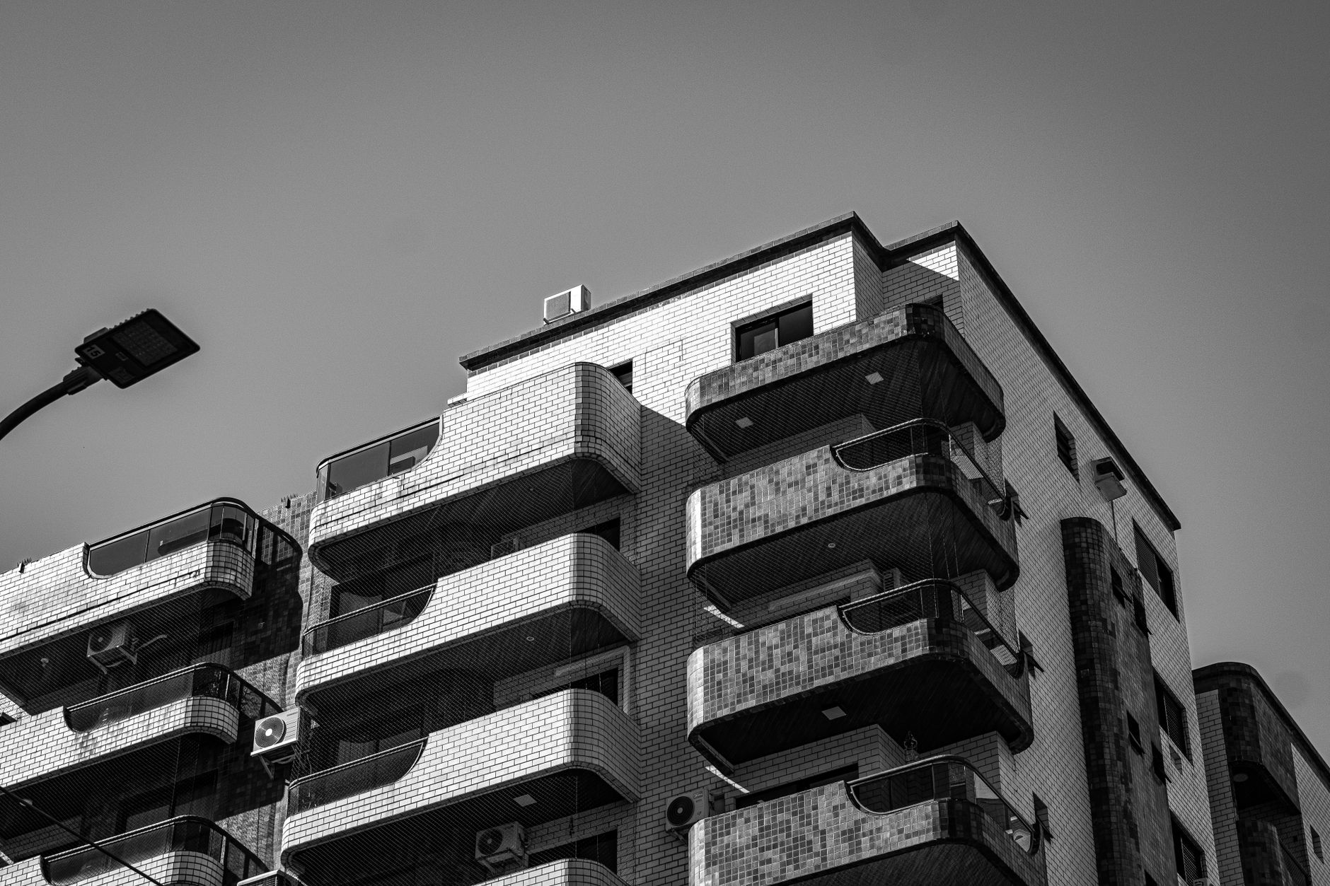 Fotografia impressionante em preto e branco de um moderno edifício de apartamentos urbanos, que exibe um design arquitetônico único.