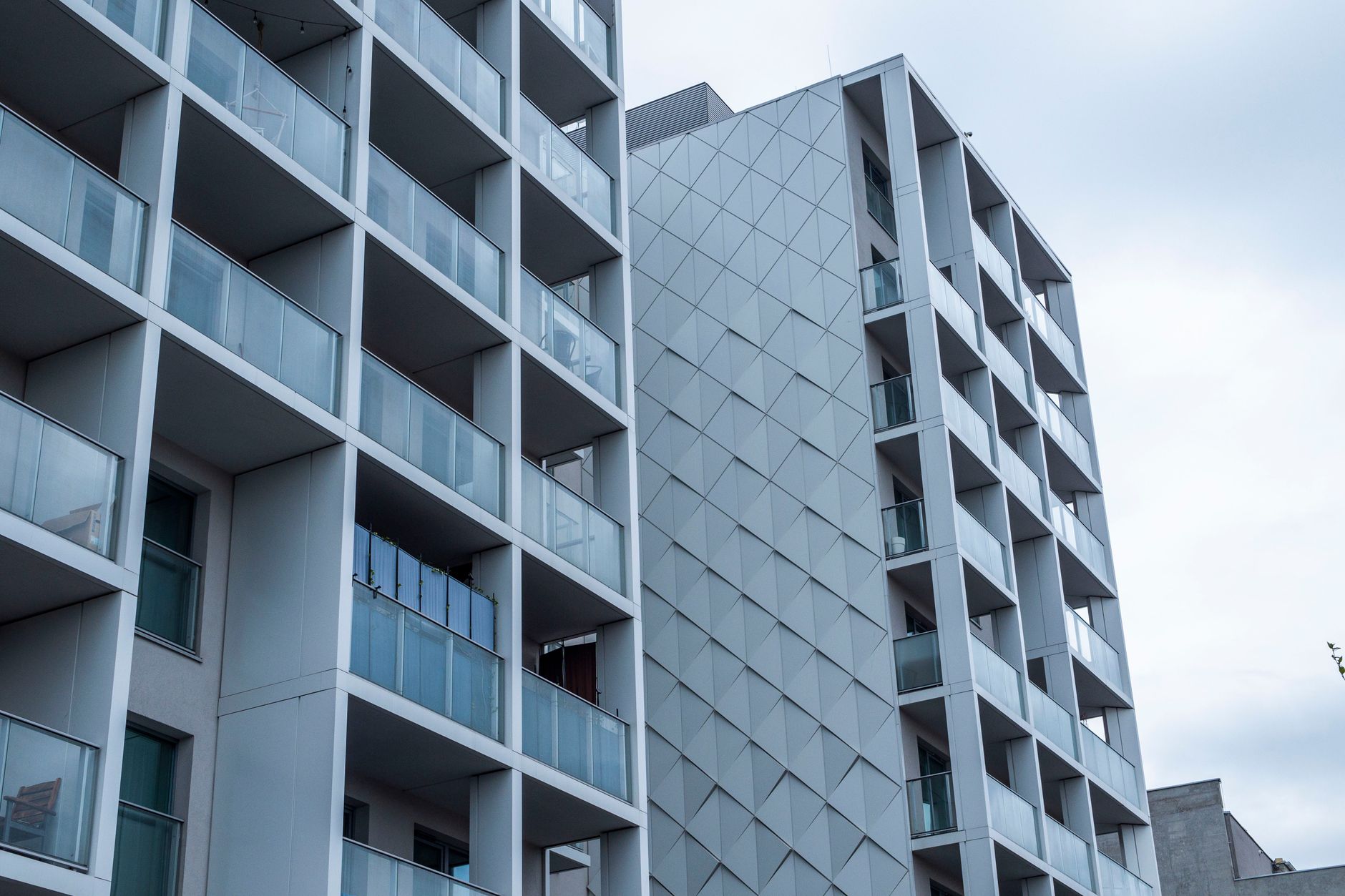 Fachada de vidro contemporânea de um prédio de apartamentos na cidade sob um céu nublado.