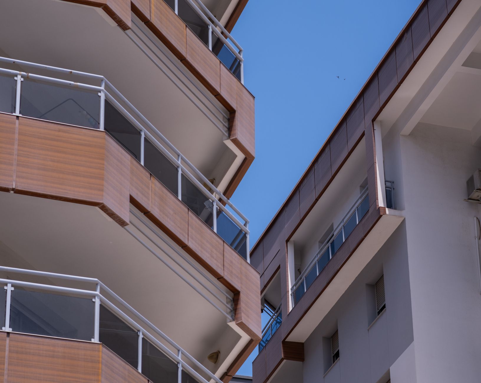 Close-up de prédios de apartamentos modernos em Izmir, destacando detalhes arquitetônicos e o céu azul.