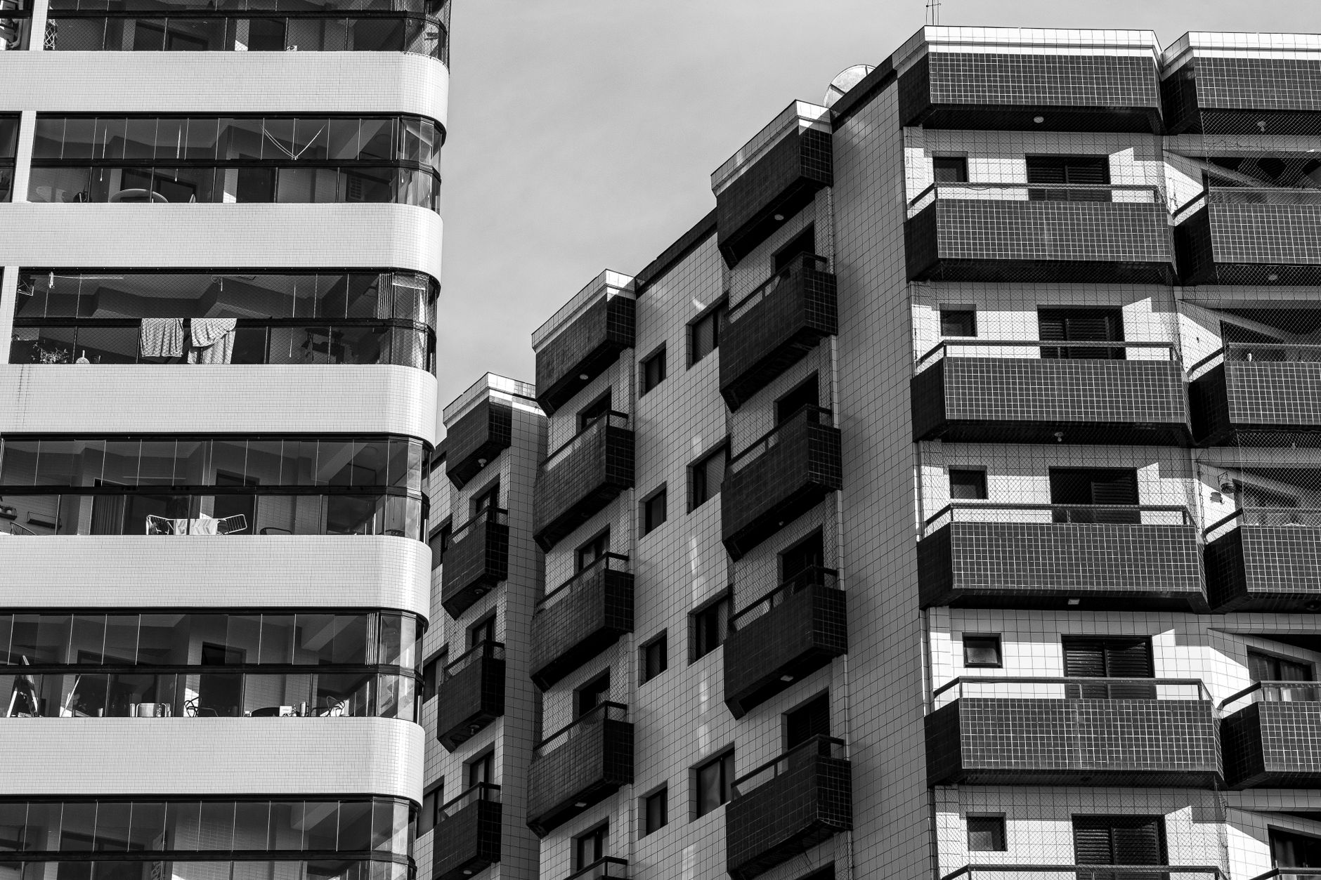 Fotografia monocromática de edifícios residenciais de vários andares, exibindo arquitetura moderna e varandas.