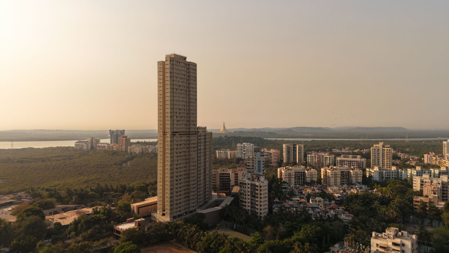 Uma foto aérea deslumbrante do horizonte de Mumbai, com seus prédios altos e vegetação exuberante ao pôr do sol.