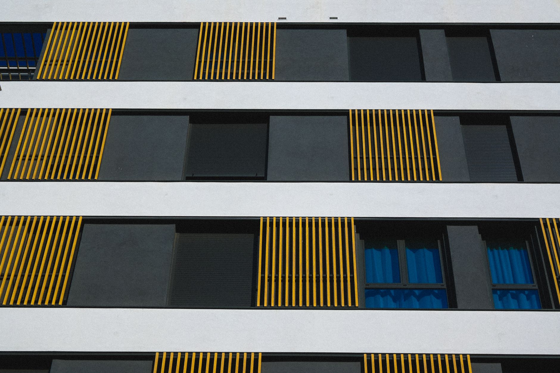 Fachada contemporânea do edifício com elegantes listras verticais amarelas nas janelas.